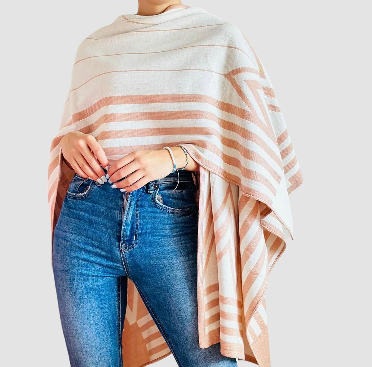 Chal doble faz tejida para mujer en tonos marfil y beige rosado, con diseño geométrico de rayas, abierta y combinada con jeans
